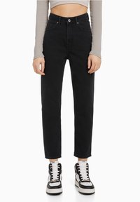 Svarta högmidjade jeans med rak ben, med framfickor, knappstängning och tillsammans med svartvita sneakers.