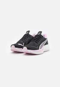 Une paire de baskets de sport noires et roses avec un design en maille, des logos de marque et des semelles rembourrées, angulées sur un fond blanc.