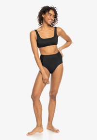Čierny rebrovaný dvojdielny bikini, ktorý obsahuje crop top s štvorcovým dekoltom a vysoko pásové nohavičky, vyrobený z elastického materiálu pre priliehavý vzhľad.