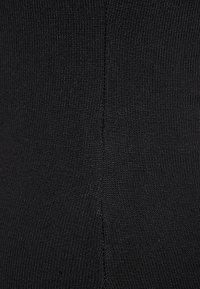 Schwarzer gerippter Stoff mit glatter Textur und sichtbaren Nahtdetails. Das Material wirkt dehnbar und figurbetont.