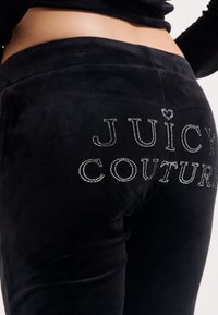 Juodas veliūro sportinės kelnės su kristalų raidėmis "JUICY COUTURE" ant nugaros, minkštas paviršius ir prigludusi forma.