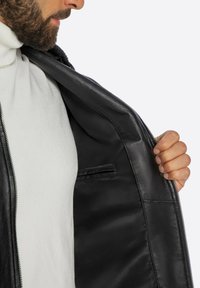 Zwarte leren jas met ritssluiting, binnenzak en zachte voering. Open kraagontwerp met een gladde, strakke textuur.