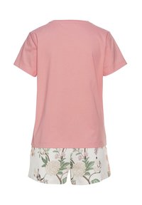Roze katoen T-shirt met korte mouwen gecombineerd met witte shorts met een bloemenpatroon in groene en roze tinten. Glad textuur, eenvoudig ontwerp.