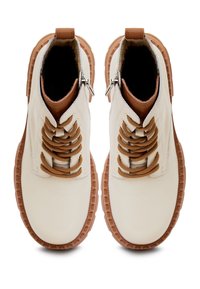 Białe skórzane botki za kostkę z brązowymi sznurowadłami i akcentami, z teksturowaną gumową podeszwą i zamkiem błyskawicznym z boku.