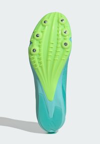 Cleated athletic shoe sole, featuring a bright green rubber bottom with multiple studs, streamlined design, and an aqua upper section.