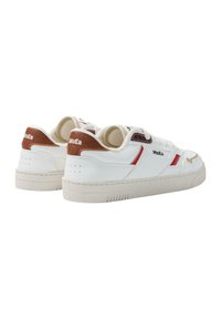 Hvite skinnsneakers med brune detaljer, røde striper og teksturerte såler. Har polstret krage og merkevarenavn på sidepanelet.