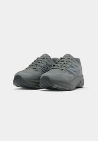 Par tenisica za sport marke New Balance u sivoj boji s gornjim dijelom od mrežaste tkanine i podstavljenim potplatom, prikazanih iz kuta sprijeda na bijeloj pozadini.