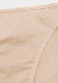 Slip in cotone beige con una texture liscia, vita elastica ondulata e cuciture rifinite per un comfort ottimale.