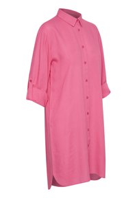 Robe-chemise rose à manches longues avec boutons, manches retroussées et col classique, présentée sur un fond blanc.