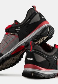 Szare i czarne buty turystyczne z czerwonymi akcentami, z metką Gore-Tex, teksturowanym materiałem i wytrzymałymi gumowymi podeszwami dla lepszej przyczepności.