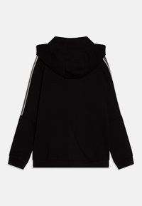 Felpa nera con una vestibilità rilassata, caratterizzata da un ampio cappuccio, maniche lunghe e strisce bianche ai lati. Realizzata in un tessuto morbido con una texture liscia.