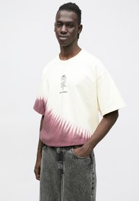 Koszulka z krótkim rękawem w kolorze gradientowym, od kremowego na górze przechodząca w głęboki burgund na dole, z nadrukiem graficznym umieszczonym na środku klatki piersiowej.