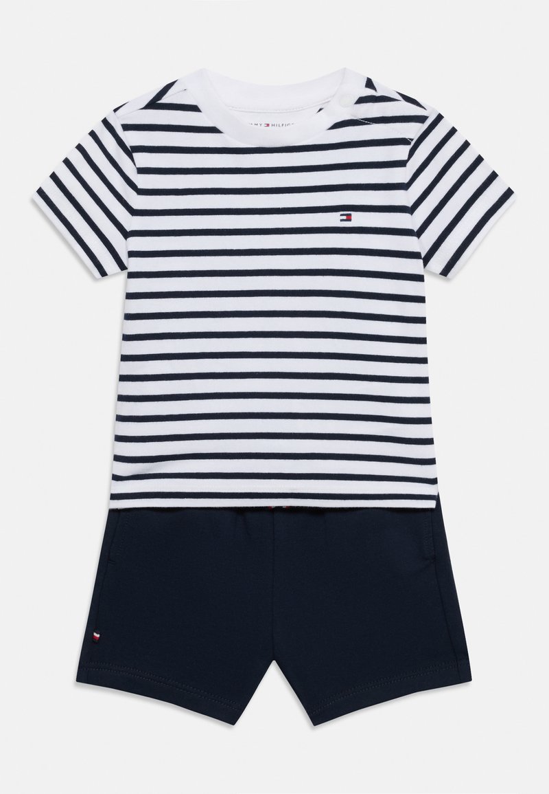 Ριγέ μπλουζάκι με κοντά μανίκια σε λευκό και ναυτικό μπλε με στρογγυλή λαιμόκοψη και λεπτομέρεια με κουμπί. Συνδυάζεται με ναυτικά μπλουτζίνια, και τα δύο κατασκευασμένα από μαλακό ύφασμα.