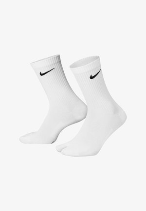 Calcetines deportivos blancos de mezcla de algodón, con textura acanalada y altura hasta la mitad de la pantorrilla, con el logo de Nike en negro en el costado.