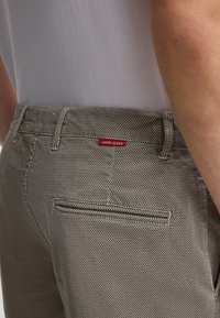 Jeans a righe grigio chiaro con finitura testurizzata, dotati di un'etichetta rossa con il logo JOOP! JEANS sulla tasca posteriore e una tasca welt posteriore.