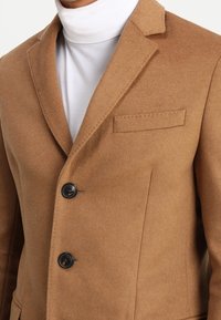 Brauner Wollmischung-Blazer mit Reverskragen, drei Knöpfen und einer Brusttasche. Verfügt über eine glatte Textur und eine taillierte Passform.