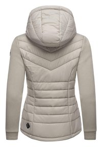 Lys beige foret jakke med hætte, prydet med chevron syninger, glatte ærmer og et logo patch ved kanten. Blød tekstur og strømlinet design.