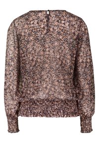 Blouse longue à manches longues en voile transparent avec poignets et ourlet élastiques, présentant un petit motif floral dans des tons roses pâles, beige et marron.