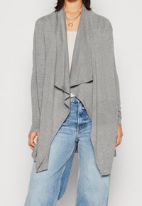 Gray open-front cardigan in lightweight, soft fabric with draped design and long sleeves, paired with high-waisted blue jeans.