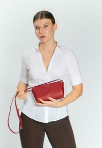 Borsa a tracolla in pelle rossa con texture a granuli, forma rettangolare, tracolla corta e dettagli metallici dorati.