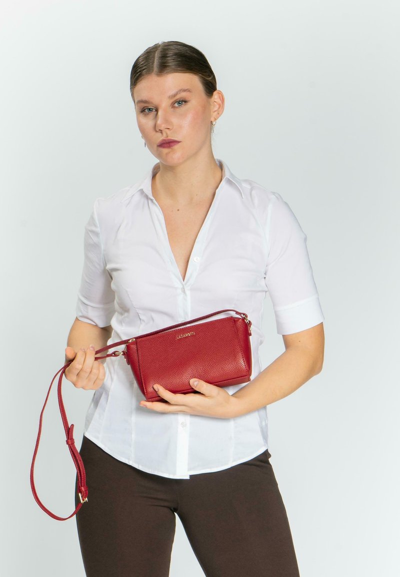 Borsa a tracolla in pelle rossa con texture a granuli, forma rettangolare, tracolla corta e dettagli metallici dorati.