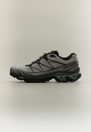 Сиво-черна обувка Salomon за трейл бягане с цветни връзки, обозначение Gore-Tex и здрава подметка с грайфер, показана в профил.