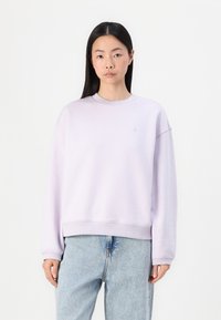 Sweatshirt de culoare violet deschis, cu guler rotund ribetat și design cu umeri lăsați. Prezintă un mic logo brodat pe piept. Croială lejeră.