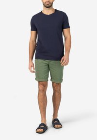Navy v-neck t-shirt, green rolled shorts, and dark sandals with strap detail. Cotton material, casual fit, displayed standing upright.