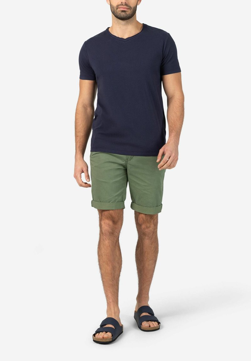 Navy v-neck t-shirt, green rolled shorts, and dark sandals with strap detail. Cotton material, casual fit, displayed standing upright.