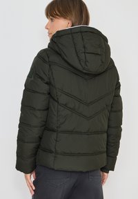 Mørkegrøn pufferjakke med hætte, der har en chevron quiltet design, syede detaljer og et mærke på venstre ærme.