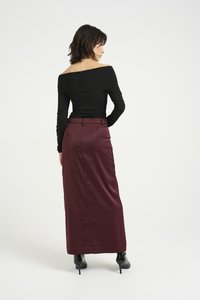 Svart off-the-shoulder topp kombinert med en burgunder, høyt liv satin maxi skjørt. Outfiten fullføres med svarte høye hæler.