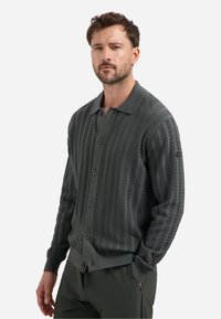 Grijze gebreide cardigan met een gemêleerd patroon, knoopsluiting aan de voorkant en kraag. Voorzien van bruine knopen en een klein logo op de mouw.