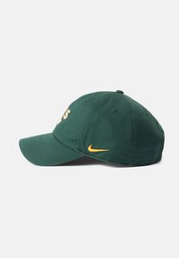 Zelena tekstilna baseball kapica s zakrivljenim vizirom, koja sadrži žuti izvezeni logo i dizajn koji se prilagođava obliku glave. Nema dodatnih akcenata vidljivih.
