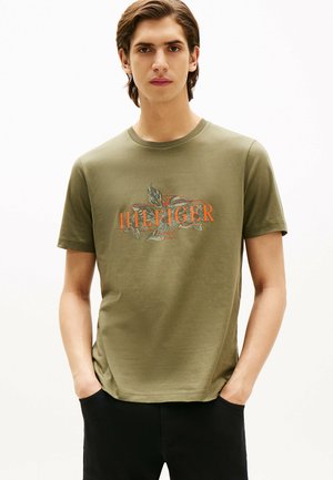 Oliven grøn bomulds-t-shirt med et farverigt "HILFIGER" logo og bladgrafik. Korte ærmer, rund halsudskæring og en afslappet pasform.