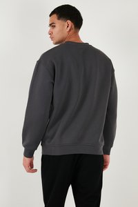 Sudadera gris con mangas largas y puños acanalados, con un escote redondo y un corte relajado. Tejido suave con una textura lisa.
