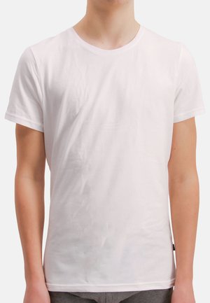 Uomo con indosso una maglietta bianca semplice a maniche corte e collo rotondo, mostrato dal collo fino ai fianchi su uno sfondo bianco.