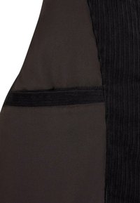 Mustast kangast, millel on sile tekstuur ja vertikaalne soonik. Kõrval on väike tasku, mille serv on pehme musta äärisega.