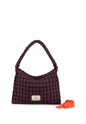 Borsa trapuntata viola scuro con texture imbottita, una singola maniglia, una targhetta in metallo e una tracolla arancione brillante staccabile accanto.