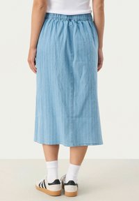 Svetlo modra denim midi krila z navpičnimi belimi črtami, elastičen pas in ravna kroja, v kombinaciji z belimi nogavicami in čevlji.