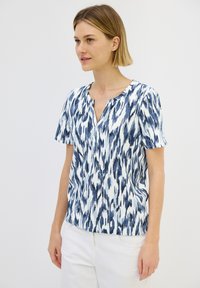 Blusa a maniche corte con motivo ikat blu e bianco, caratterizzata da un collo rotondo e un tessuto morbido e testurizzato.