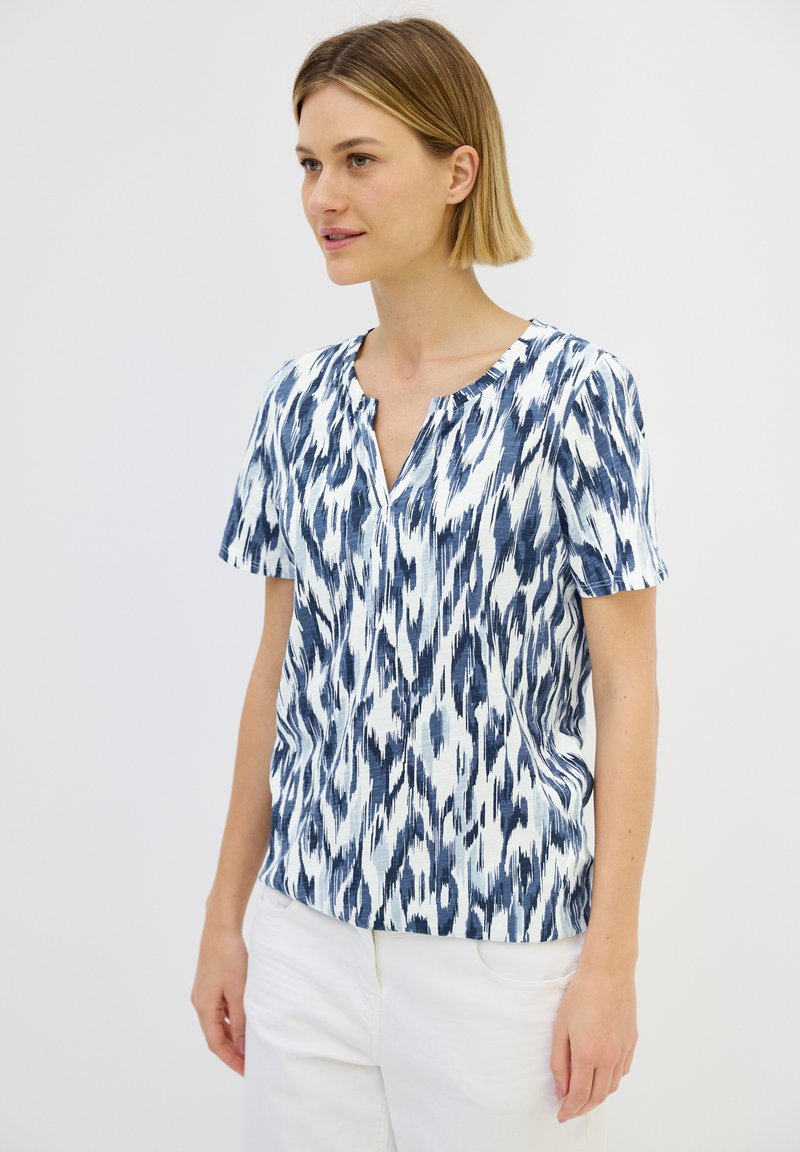 Blusa a maniche corte con motivo ikat blu e bianco, caratterizzata da un collo rotondo e un tessuto morbido e testurizzato.