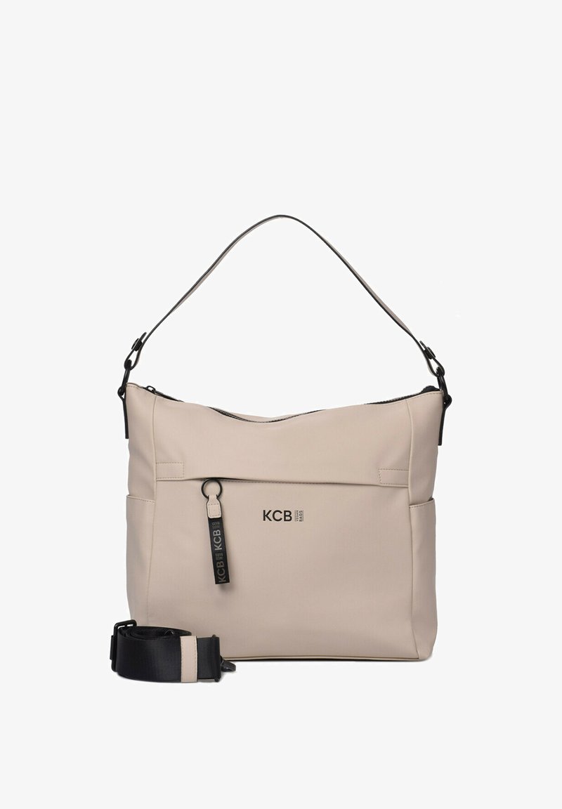 Bolso de hombro de nailon beige con acentos negros, correa ajustable, cierre de cremallera en la parte superior y detalle del logo KCB en la parte frontal.