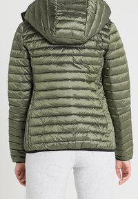 Gevoerde olijfgroene jas met een capuchon, met een horizontaal gegarneerde textuur en zwarte afwerking aan de zoom. Geschikt voor koudere weersomstandigheden.
