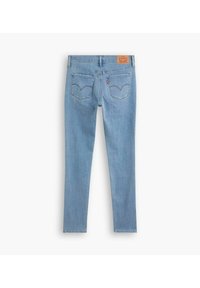 Jeans de mezclilla azul claro con un diseño ajustado, dos bolsillos traseros con acentos de costura y una etiqueta de logo marrón en la cintura.