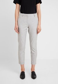 Pantalons tapered gris clair en tissu texturé, dotés de passants de ceinture et de poches latérales. Assortis à des chaussures noires à enfiler.