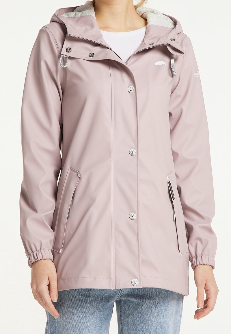 Veste imperméable rose clair avec capuche, cordon de serrage, boutons-pression, deux poches latérales zippées et une douce doublure grise. Texture lisse et manches longues.