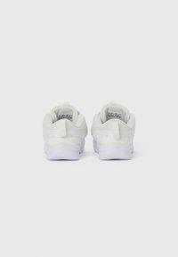 White athletic shoes with a textured mesh upper, padded collars, and rubber soles. Features a pull tab on the heel and soft cushioning.