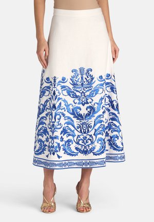 Hvid midi-nederdel med indviklede blå blomster- og ornamentmønstre langs bunden, båret med gyldne stropper.