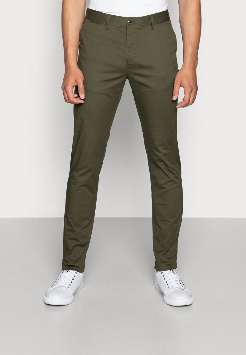 Chinos verde oliva con vestibilità diritta, realizzati in tessuto misto cotone, dotati di tasche frontali, passanti per cintura e chiusura con un solo bottone.