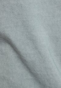 Tela de algodón azul claro con una textura suave y un patrón de cordones fino, que muestra sutiles variaciones en color y profundidad.
